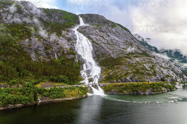 Western Norway. Langfossen cascade waterfall on the Vaule river. Passes through the highway. The photo was taken with a drone. Summer cold and rainy day