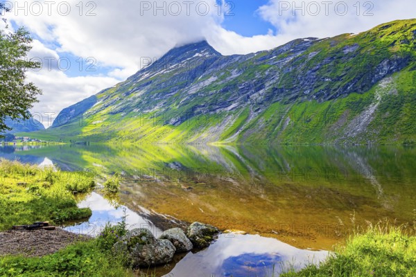 Deep lake with clean transparent water. The water reflects lush clouds, blue skies and forested shores. Eidsvatnet - majestic lake in Norway. Northern summer in Scandinavia