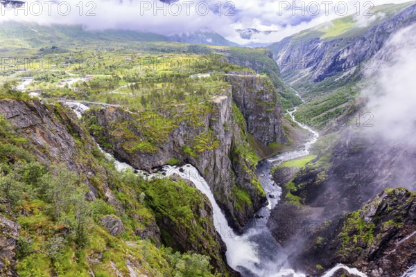 Voringsfossen is a majestic waterfall on the Hardangerfjord. The waterfall falls into a narrow deep picturesque gorge. Rainy cold July in Norway
