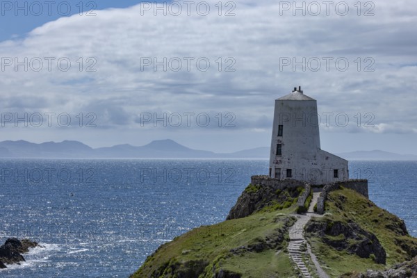 Twr Mawr Lighthouse, white lighthouse on a hill by the sea with blue sky and clouds, Ynys Llanddwyn, Newborough, Anglesey, Wales, Great Britain
