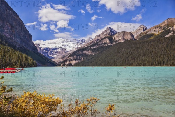 Lake Louise on a beautiful sunny day. The lake is surrounded by mountains, glaciers and pine forests