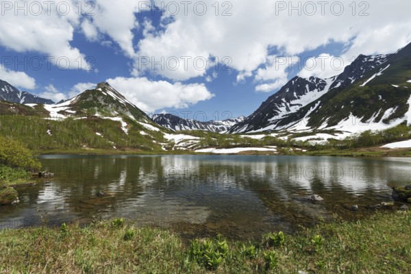 Scenery summer landscape of Kamchatka: beautiful view of Mountain Range Vachkazhets, mountain lake and clouds in blue sky on sunny day. Eurasia, Russian Far East, Kamchatka Peninsula