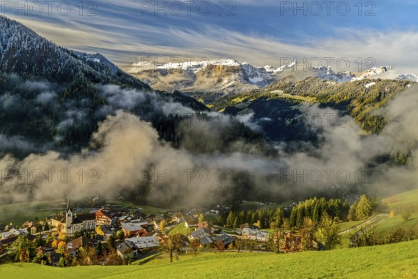 Autumn landscape with colorful trees and snowy mountains in the background in Dolomites