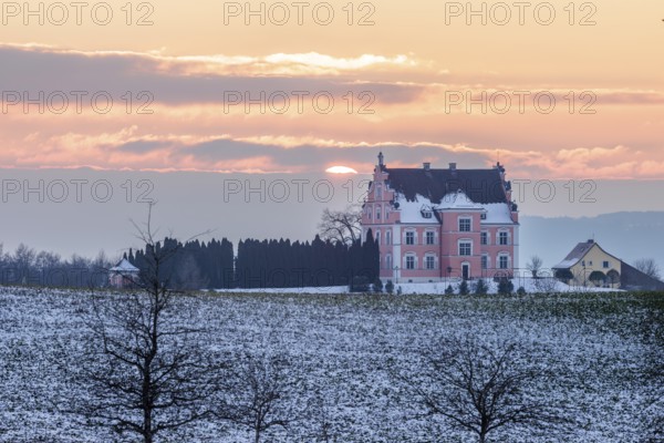 A castle in the middle of snow-covered fields at sunset with a cloudy sky, Freudental Castle, Allensbach, Lake Constance, Baden-Württemberg, Germany