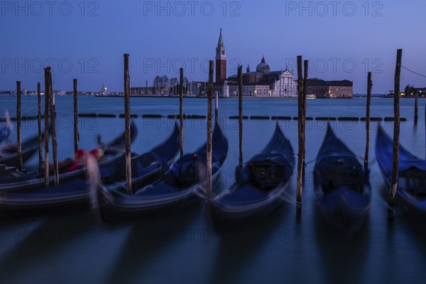 Venetian gondolas, boat dock at St Mark's Square, church of San Giorgio Maggiore in the background, blue hour, long exposure, Venice, Veneto, Italy