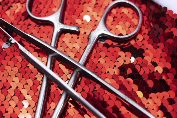 Surgical instruments resting on bright red sequins