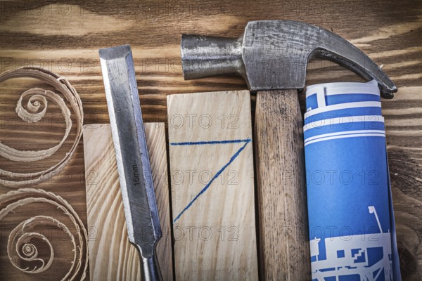 Blue rolled construction drawing claw hammer firmer chisel wooden studs curled shavings on vintage wood board