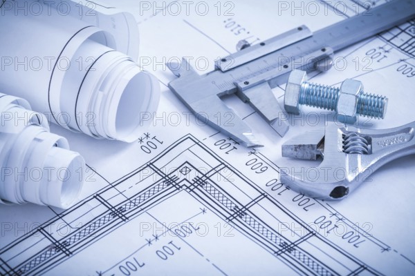 Screw bolt with nut adjustable spanner slide caliper rolls of construction plans on blueprint architecture and building concept