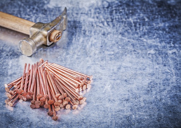 Vintage claw hammer heap of brass construction nails on metallic background