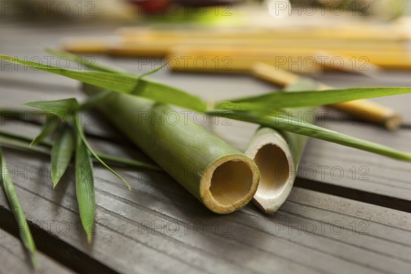 Round bamboo sticks with leaves on wooden background. Ecological raw material