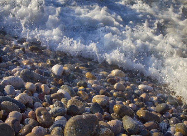 Beach of multi-colored round pebbles, and the splash of salty waves. Black sea, Caucasus