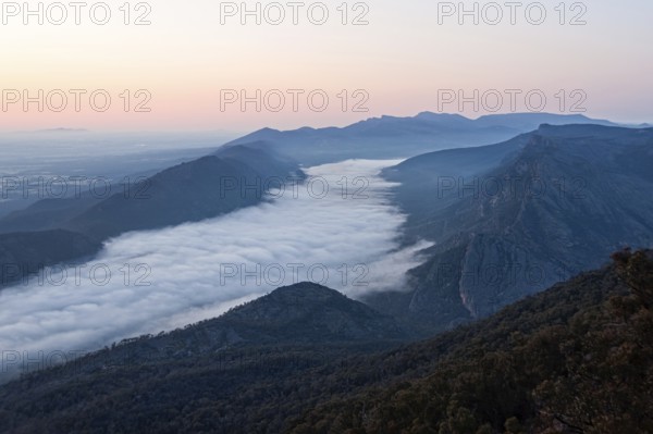 Clouds in the valley and the Wonderland Range at sunrise photographed from the Boroka Lookout in the Grampians, Victoria, Australia