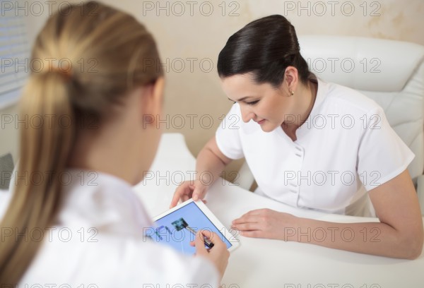 Two woman beauticians in the office room talking about job using tabet PC