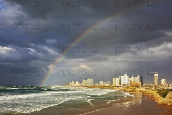 Storm cloud hanging over the sea, gorgeous huge rainbow crossed the sky. Promenade and beach in Tel Aviv