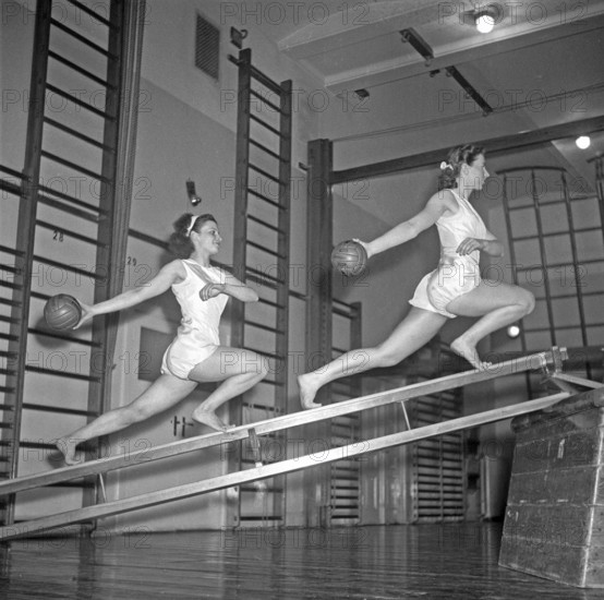 Gymnastics in the 1940s. Two young women are balancing on gymnasium equipment and at the same time synchronizing their movements holding balls. 1940s Sweden Photo Kristoffersson ref AN70-4