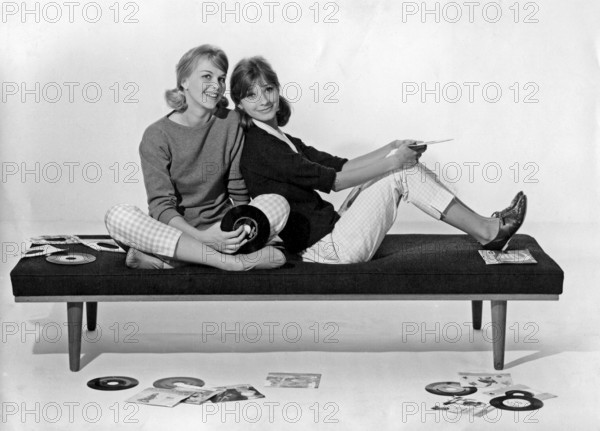 1960s lifestyle. Two girls in typical 1960s clothes are sitting together holding music records. Sweden 1960
