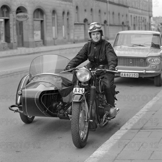 In the 1960s. A woman seen dressed in the typical motorcycle drivers outfit and helmet at her motorcycle with a sidecar for passenger. Sweden 1967