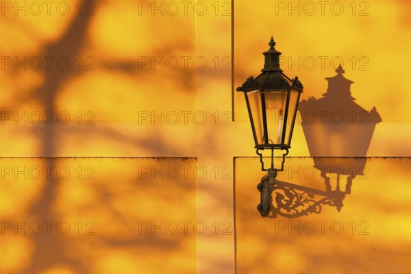 Detail of retro street light on the wall at sunset. Prague, Czech Republic