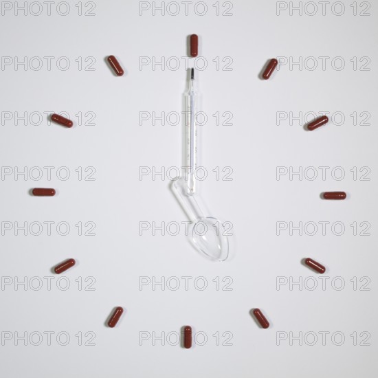 Time - Clock of twelve pills, medical thermometer and plastic spoon