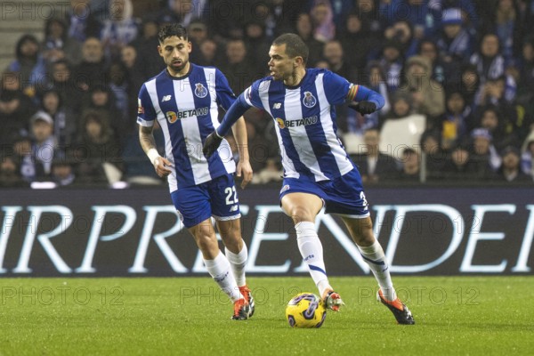 Football match, PEPE FC Porto on the right running with the ball to the left, VARELA FC Porto on the left watching the action, Estadio do Dragao football stadium, Porto, Portugal
