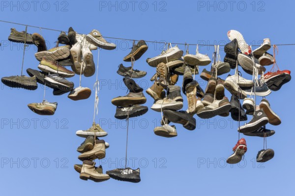 Shoes, boots, trainers, ... hanging on a rope in the air above the Grapengießerstraße medieval old town of Lüneburg, Hanseatic city of Lüneburg, Lower Saxony, Germany