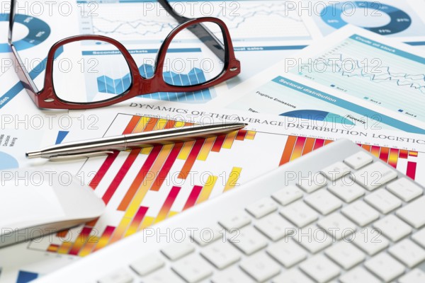 Business workplace with keyboard glasses and financial documents on table