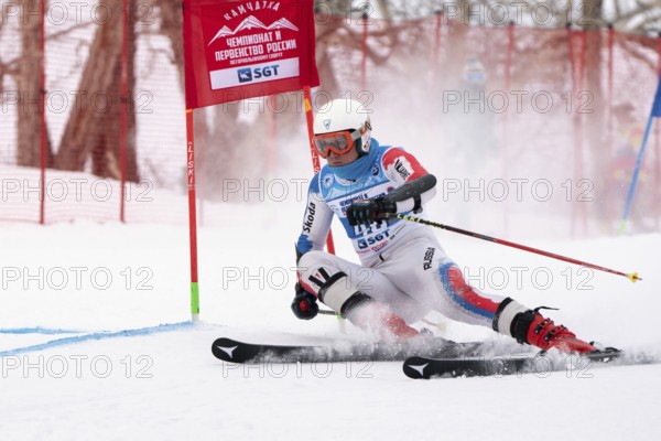 KAMCHATKA PENINSULA, RUSSIAN FEDERATION, APRIL 2, 2019: Mountain skier Ivan Chentsov Kemerovo Region skiing down snowy mountain slope. Russian Men's Alpine Skiing Championship, giant slalom