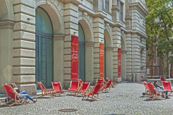 Red deckchairs and advertising banners on cobblestones in front of the Literaturhaus, Munich, Bavaria, Germany