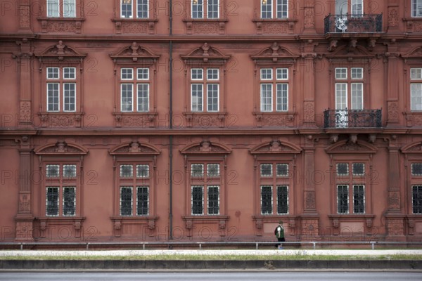 Mainz, Germany - June 24, 2015: A tourist wearing a green waistcoat and hiking clothes walks along the east facade of the Electoral Palace Mainz on 24 June 2015 in Mainz, Germany