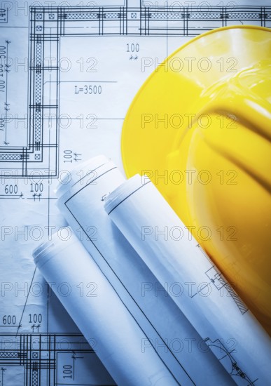 Building helmet rolled construction drawings on blueprint
