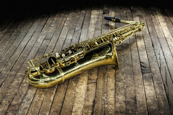 Beautiful golden saxophone lies on a wooden floor