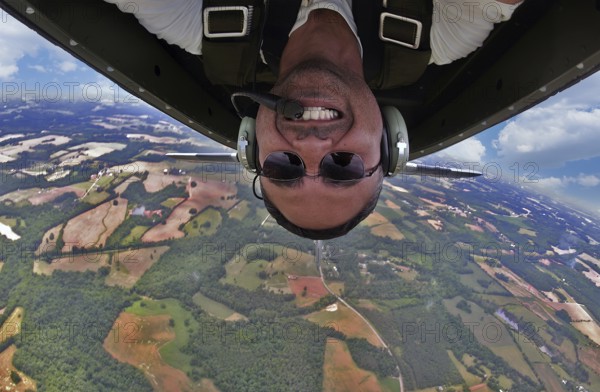 A WWII pilot captures a daring selfie mid-flight, executing precise aerial maneuvers in a classic fighter plane. The vintage cockpit and sky blur, capturing thrill and history in one shot, Concord, United States of America