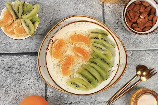 Healthy breakfast with ingredients, Rice pudding with kiwi, honey, tangerines and almonds.flat lay, Healthy and natural food concept, lifestyle, food for children, selective focus