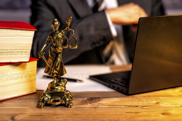 Office of a lawyer with books and a statue of Lady Justice, goddess Justitia, on the desk