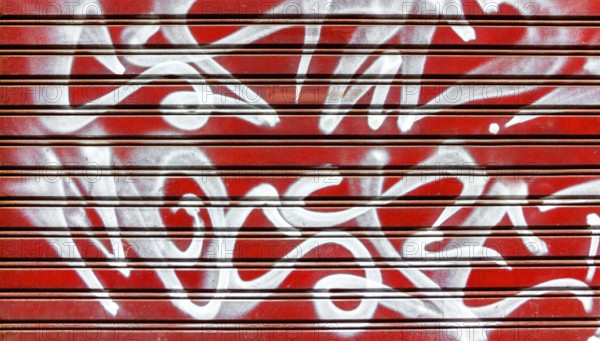 Red garage gate with vandalism sign of graffiti white spray paint. Ideal for concepts and backgrounds
