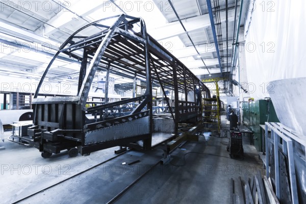 One working day of modern automatic bus trolleybus car production with unfinished cars workers in protective uniform in automotive background automobile assembly line welding arm