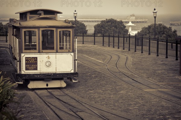 San Francisco cable car at Hyde Street turntable (Fisherman's Wharf) with foggy Aquatic Park in background, sepia toned image