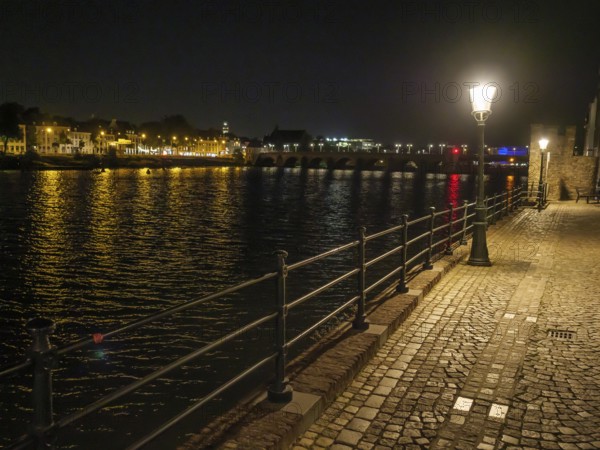 River course at night, illuminated by lights and reflecting water surface, maastricht, the netherlands