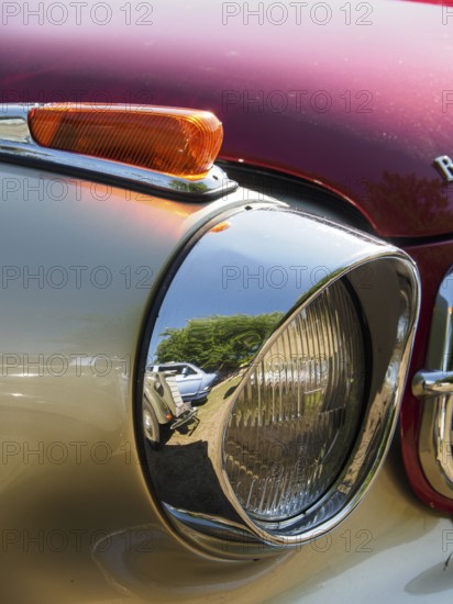 Close-up of a chrome-plated spotlight with reflection of the surroundings on a red background, Bocholt, Münsterland, Germany