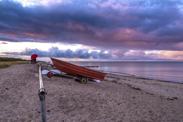 Atmospheric landscape on the Baltic Sea with a red boat and colourful clouds. Seaside with a red boat and beautiful clouds with pink and violet colours