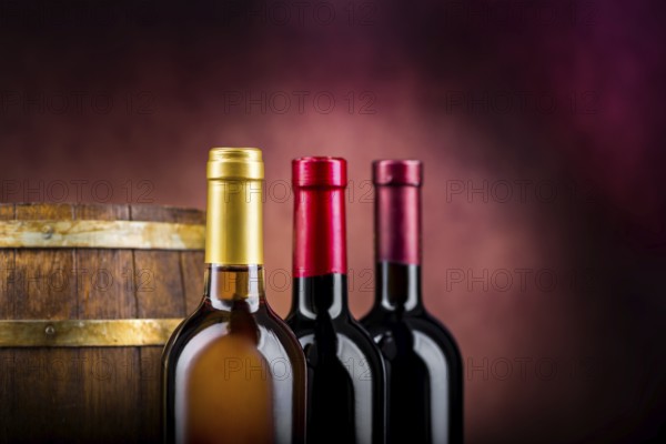Three bottles of wine and wooden barrel on a burgundy background