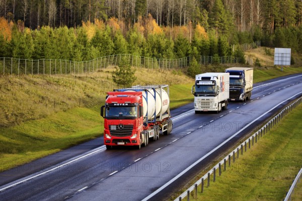 Three freight trucks transporting load along freeway on a day of autumn, elevated view. Salo, Finland. October 29, 2020
