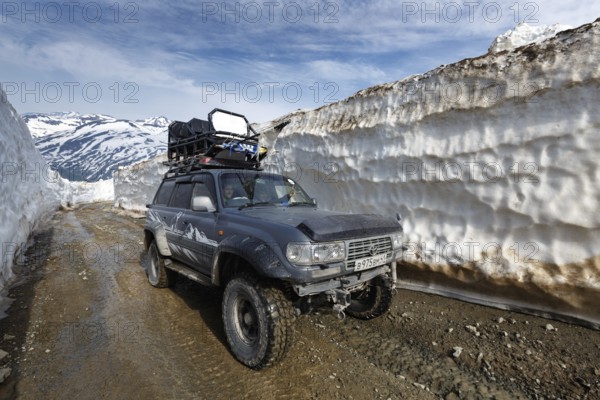 KAMCHATKA PENINSULA, RUSSIA, JUNE 18, 2017: Japanese extreme off-road expedition car Toyota Land Cruiser driving on mountain road in snow tunnel surrounded by high snowdrifts on Vilyuchinsky Pass