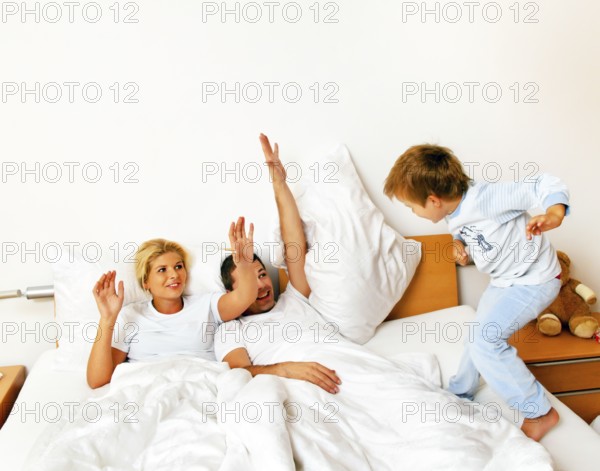 A young family lies in bed in the bedroom Austria