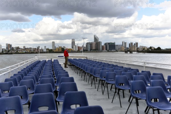 River cruise with empty chairs on the deck, modern city view in the background, London, London region, England, United Kingdom