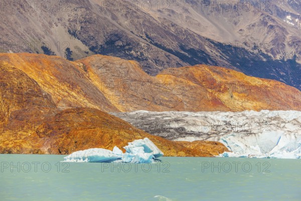Massive glacier descends into the emerald water. In the water ice-floes, broken away from a glacier. The picturesque multi-colored shore of Lake Viedma