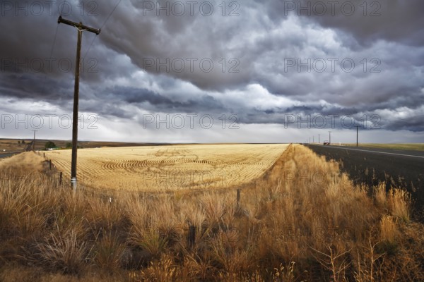Soil rural road and columns of an electric main to fields of Montana. The thunder-storm begins