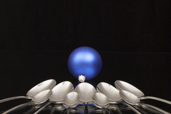 Blue Christmas decoration and nine spoons on a black glass desk