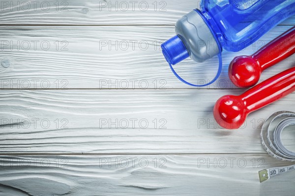 Tape measure water shaker dumbbells on wooden board fitness concept