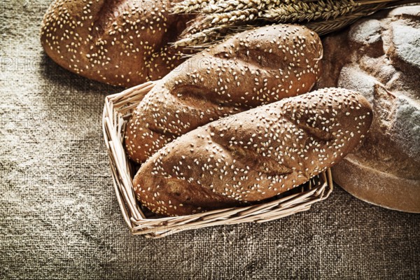 Wicker basket bread breadstick wheat ears on vintage burlap background